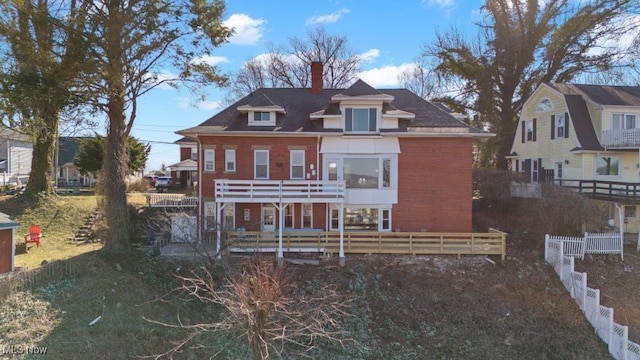 rear view of property with brick siding, fence private yard, and a chimney