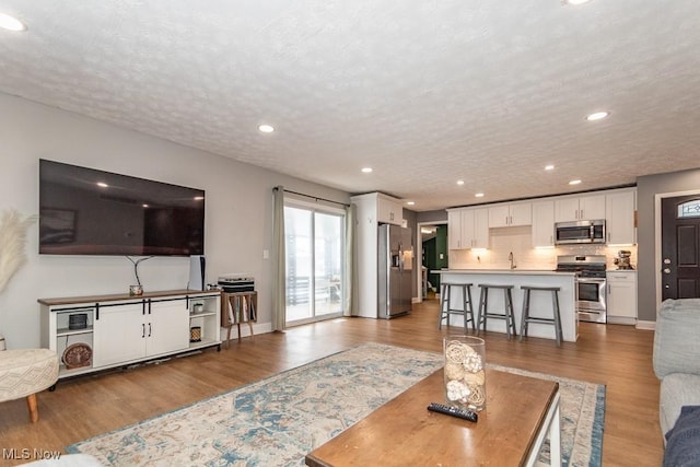 living area with recessed lighting, a textured ceiling, and wood finished floors