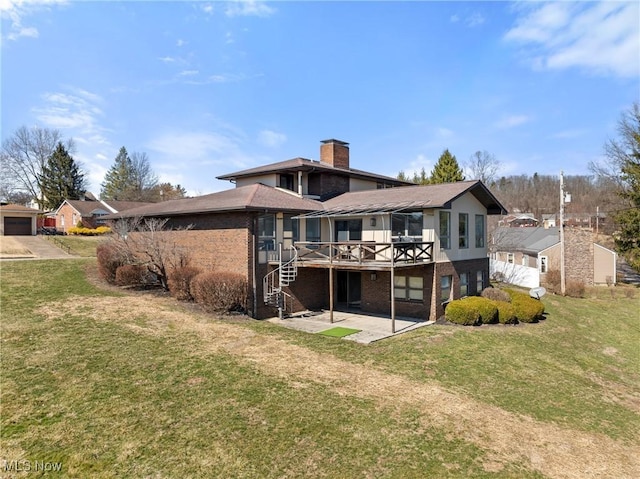 rear view of property featuring a patio, a wooden deck, a chimney, a lawn, and brick siding