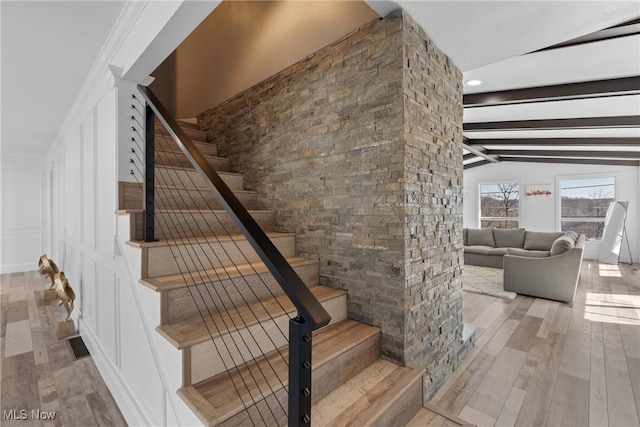 stairway featuring lofted ceiling with beams and wood finished floors