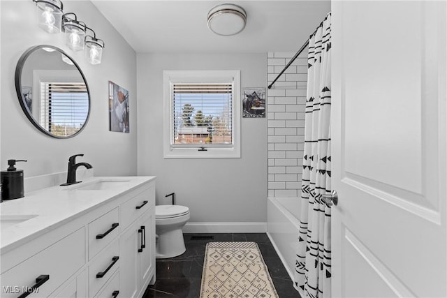 full bathroom with baseboards, double vanity, a sink, tile patterned flooring, and toilet