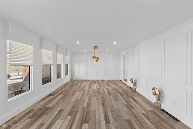 empty room with recessed lighting, light wood-type flooring, and a decorative wall