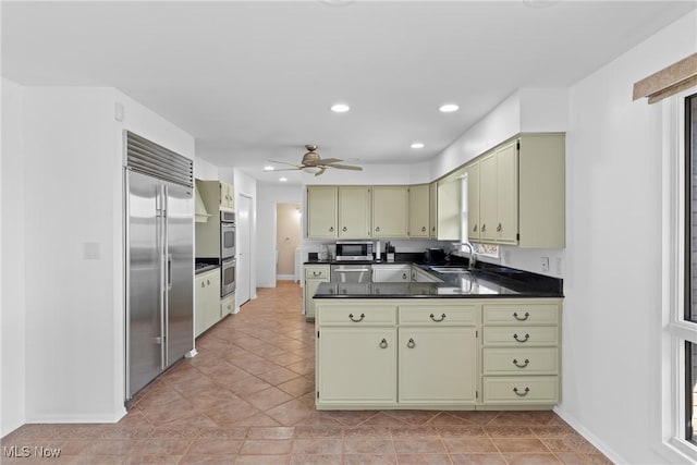 kitchen with green cabinetry, recessed lighting, stainless steel appliances, dark countertops, and cream cabinets