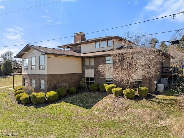 view of side of home featuring a lawn, brick siding, and a chimney