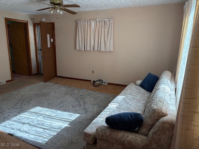 living area featuring baseboards and a ceiling fan