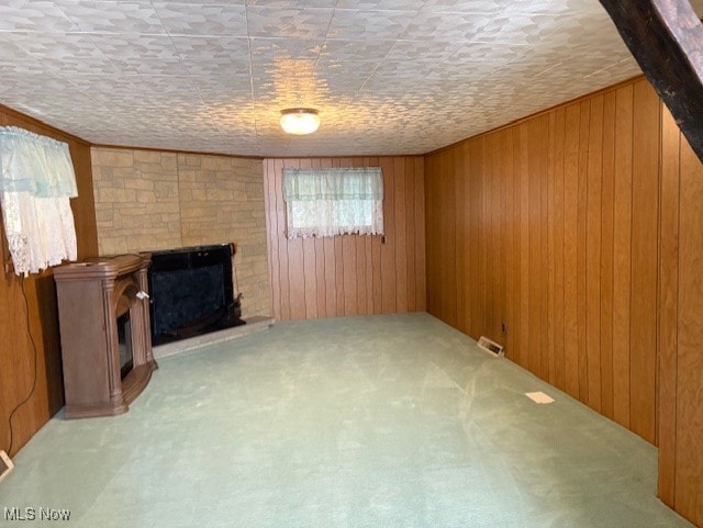 basement featuring visible vents, wood walls, and a fireplace