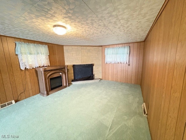 living area featuring carpet flooring, a fireplace, and wooden walls