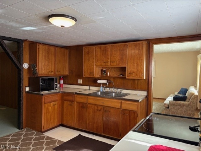 kitchen with a sink, range with electric cooktop, and brown cabinetry