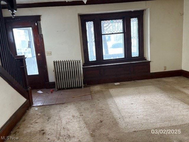 foyer entrance featuring stairway, radiator heating unit, baseboards, and plenty of natural light