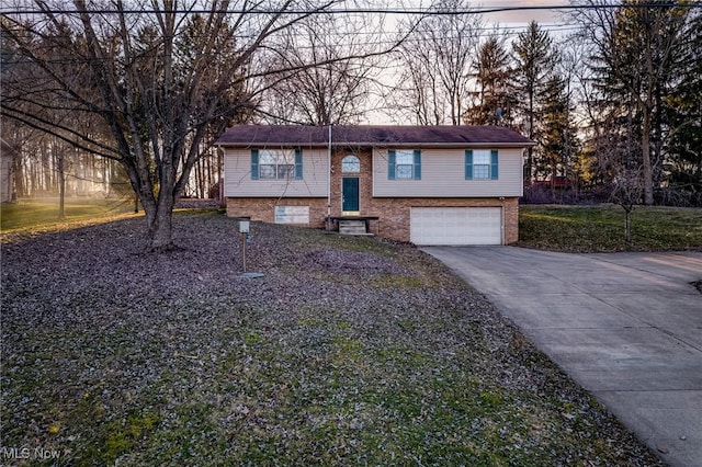 split foyer home with a garage, brick siding, and driveway