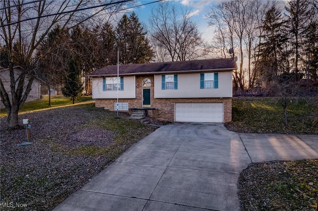 bi-level home with an attached garage, brick siding, and driveway