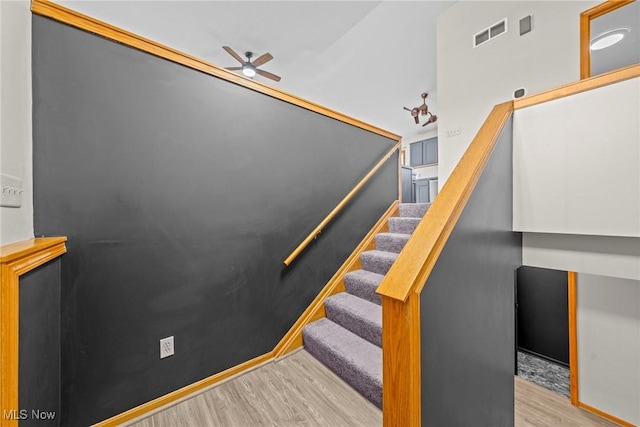 stairs with a ceiling fan, wood finished floors, and visible vents