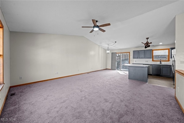 unfurnished living room featuring baseboards, lofted ceiling, carpet floors, and a ceiling fan