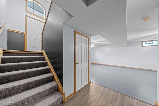 stairway with a textured ceiling and wood finished floors