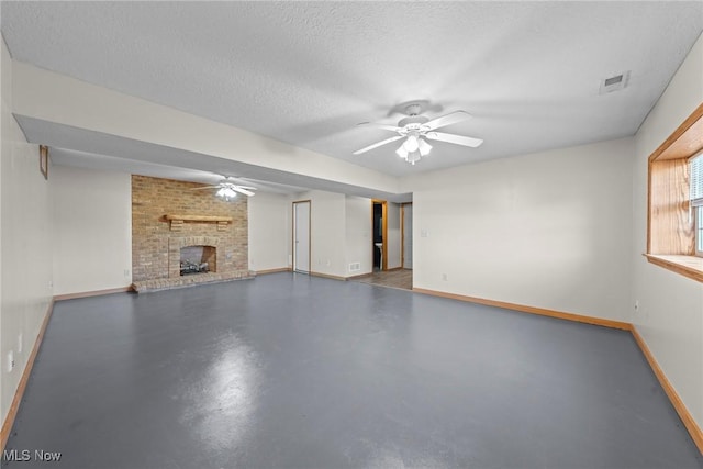 unfurnished living room featuring visible vents, concrete floors, ceiling fan, a fireplace, and a textured ceiling