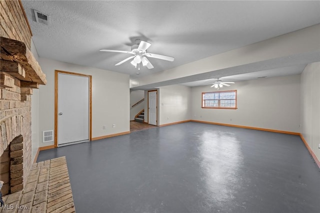 below grade area with stairway, a ceiling fan, visible vents, a textured ceiling, and a brick fireplace