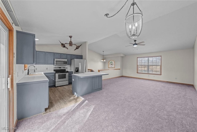 kitchen with a sink, a kitchen island, appliances with stainless steel finishes, light countertops, and lofted ceiling