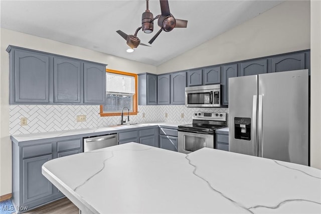 kitchen with a sink, decorative backsplash, appliances with stainless steel finishes, and vaulted ceiling