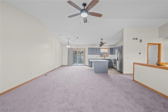 unfurnished living room featuring visible vents, baseboards, ceiling fan, light colored carpet, and lofted ceiling