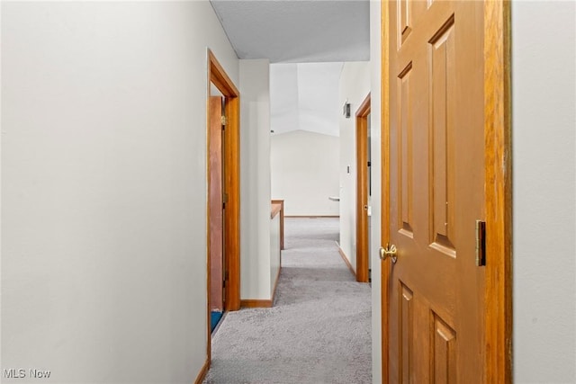 hallway with baseboards, carpet, and vaulted ceiling