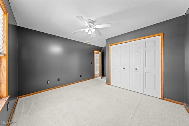 unfurnished bedroom featuring baseboards, carpet floors, a closet, and ceiling fan