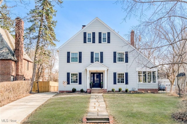 view of front of property featuring a chimney, a front lawn, and fence