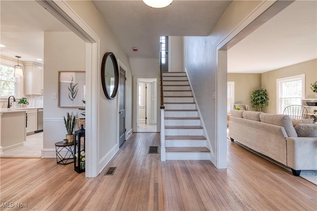 stairway with hardwood / wood-style floors, a healthy amount of sunlight, and visible vents