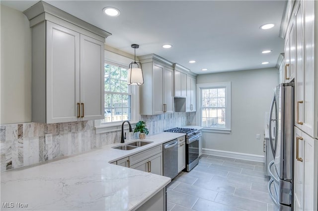 kitchen with a sink, decorative light fixtures, appliances with stainless steel finishes, decorative backsplash, and light stone countertops