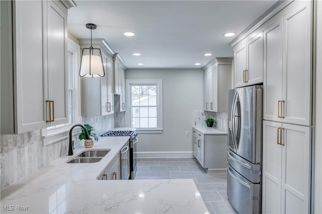 kitchen featuring light stone countertops, a sink, decorative backsplash, stainless steel appliances, and pendant lighting