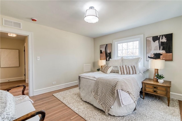 bedroom with visible vents, light wood-style flooring, and baseboards