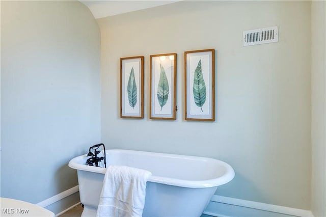 full bathroom featuring visible vents, baseboards, and a freestanding bath