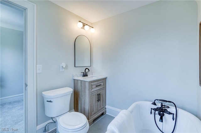 bathroom featuring toilet, a freestanding bath, vanity, and baseboards