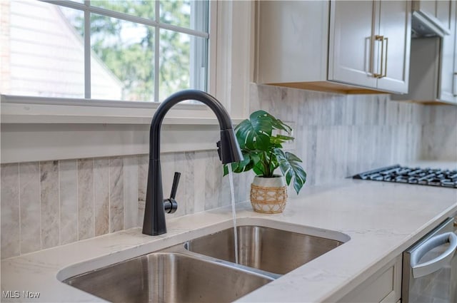 interior details featuring light stone counters, backsplash, and a sink