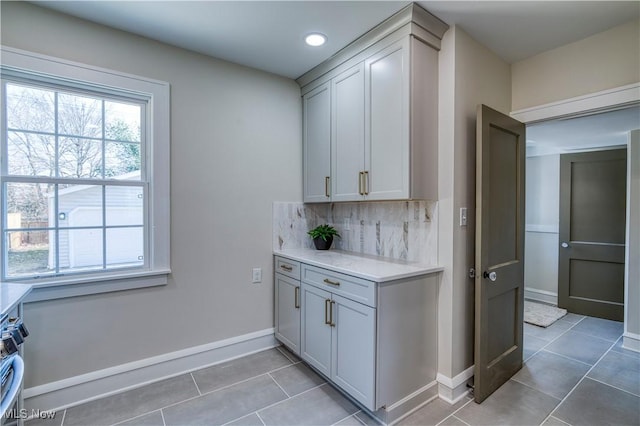 kitchen with light tile patterned floors, baseboards, backsplash, and light countertops