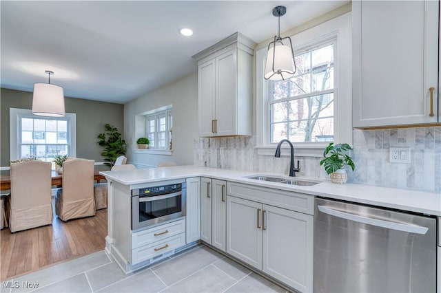 kitchen featuring tasteful backsplash, light countertops, light tile patterned floors, stainless steel appliances, and a sink