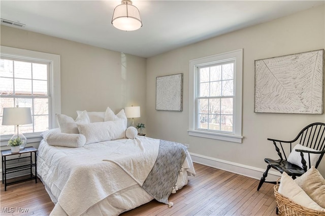 bedroom featuring visible vents, baseboards, and hardwood / wood-style flooring