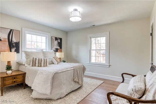 bedroom with visible vents, baseboards, and wood finished floors