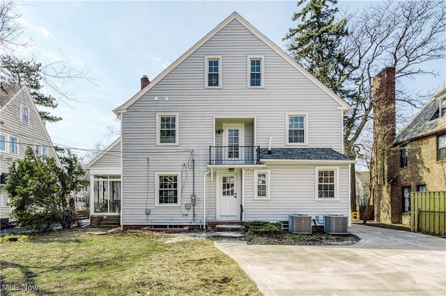 back of property with cooling unit, a balcony, and a yard