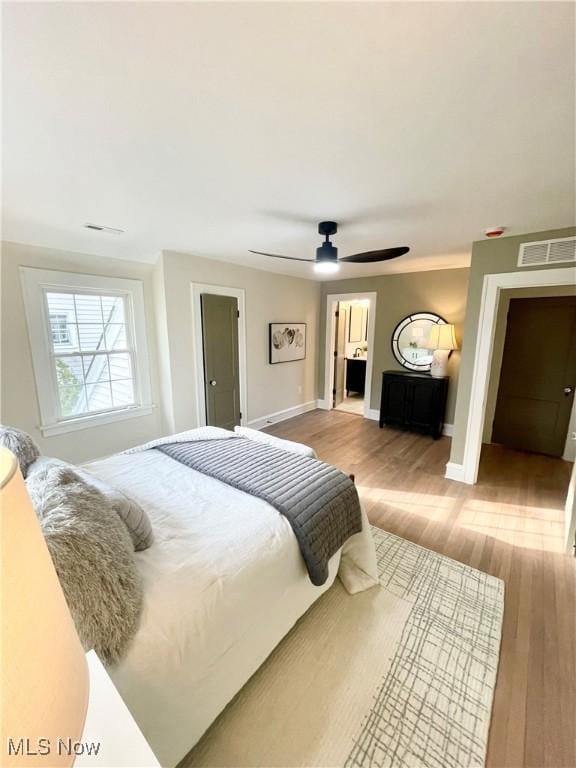 bedroom featuring wood finished floors, visible vents, and baseboards