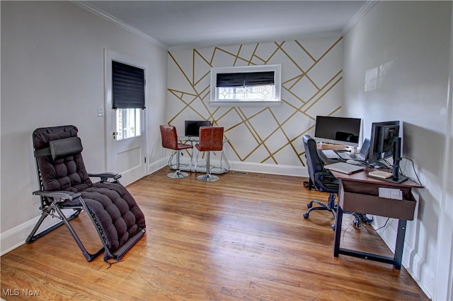 office with baseboards, wood finished floors, an accent wall, and ornamental molding