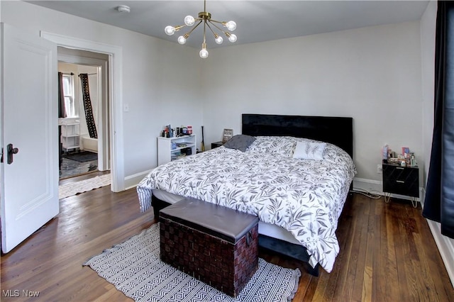 bedroom with a notable chandelier, dark wood-type flooring, and baseboards