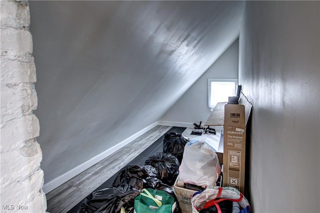 interior space featuring lofted ceiling, wood finished floors, and baseboards