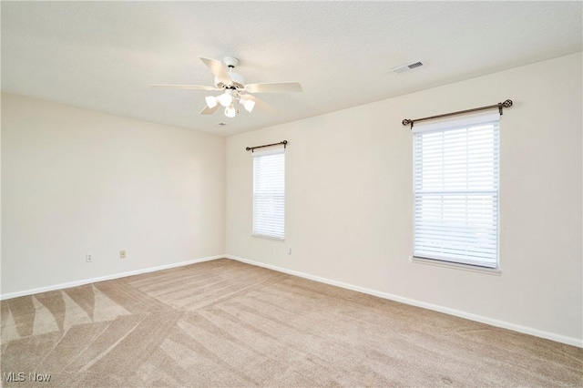 carpeted empty room with visible vents, baseboards, and ceiling fan