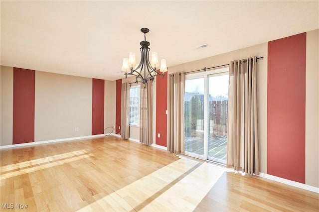 spare room with visible vents, baseboards, an inviting chandelier, and light wood-style flooring