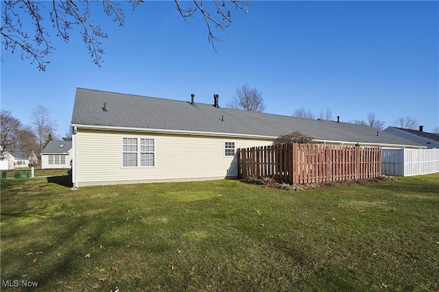 back of property featuring a lawn and fence