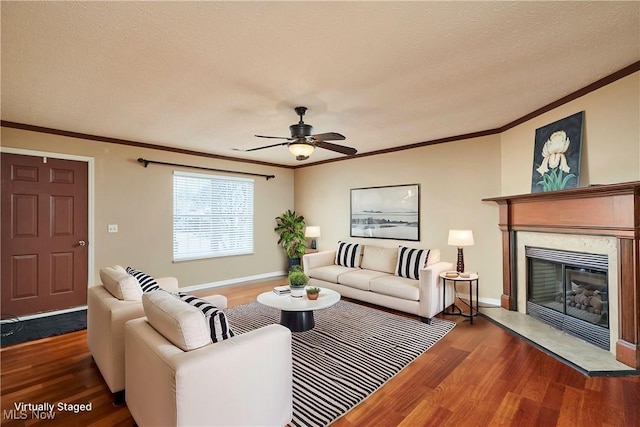 living room featuring ornamental molding, a ceiling fan, a textured ceiling, wood finished floors, and a fireplace