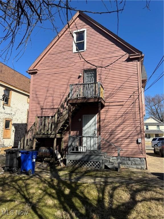 back of property featuring stairway and a lawn