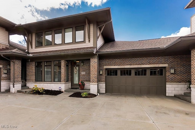 view of front of house with brick siding, an attached garage, a shingled roof, and concrete driveway