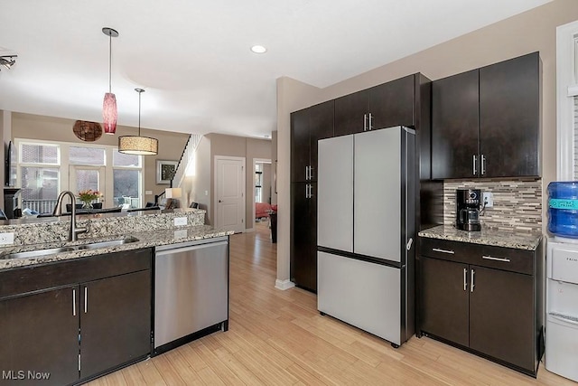 kitchen with dishwasher, light wood-type flooring, freestanding refrigerator, and a sink