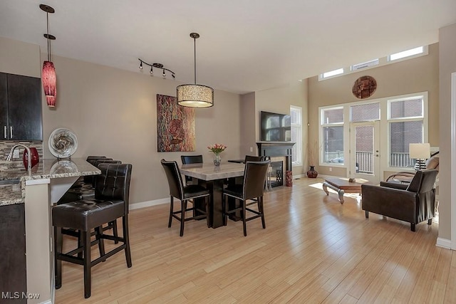 dining area with a glass covered fireplace, baseboards, and light wood-style flooring